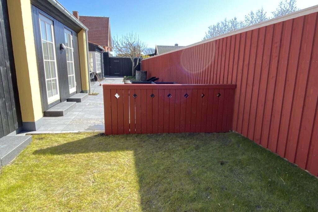 Nymalet rød træfacade på gårdsplads i Skagen
